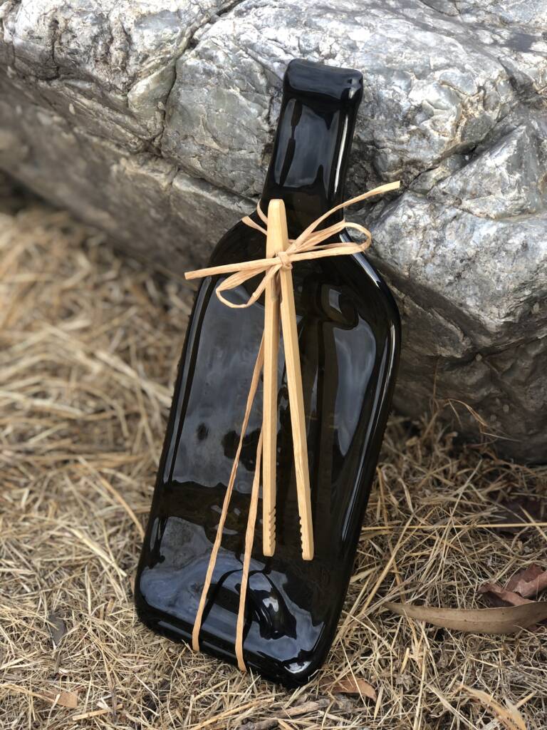 Cheeseboard made from wine bottle leans against rock